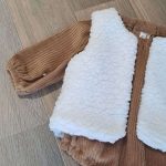 Barboteuse bébé garçon aux manches longues en velours grosse côte uni Camel avec par dessus un gilet de berger bebe une face imitation fourrure de mouton et l'autre face en double gaze à motif.