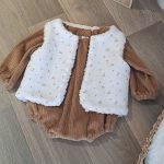 Barboteuse bébé garçon aux manches longues en velours grosse côte uni Camel avec par dessus un gilet de berger une face imitation fourrure de mouton et l'autre face en double gaze à motif.