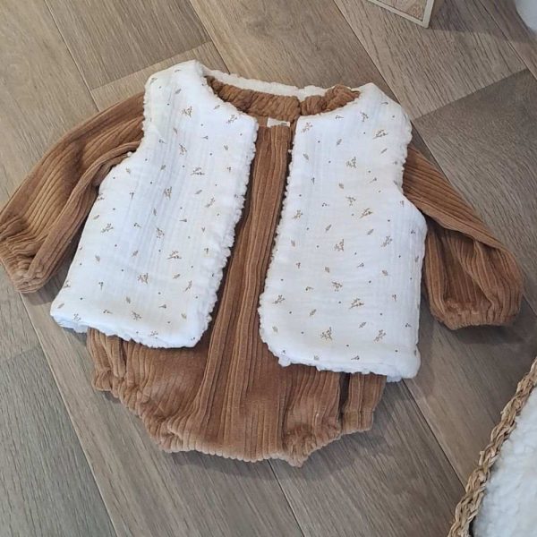 Barboteuse bébé garçon aux manches longues en velours grosse côte uni Camel avec par dessus un gilet de berger une face imitation fourrure de mouton et l'autre face en double gaze à motif.